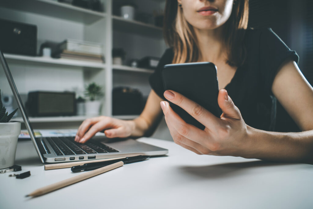 a woman using a laptop and a phone